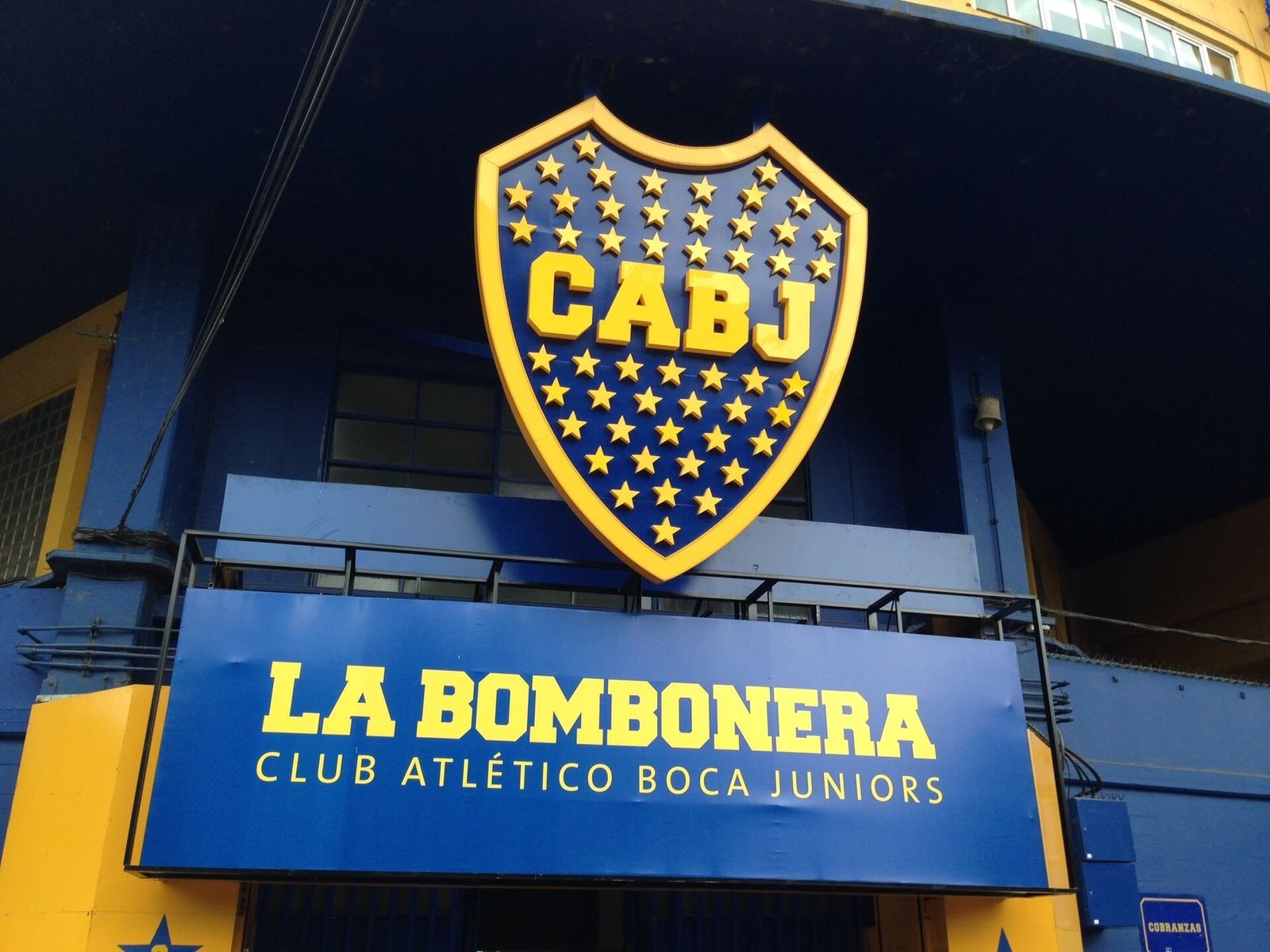 Escudo do Boca Juniors e letreiro La Bombonera na entrada do estádio