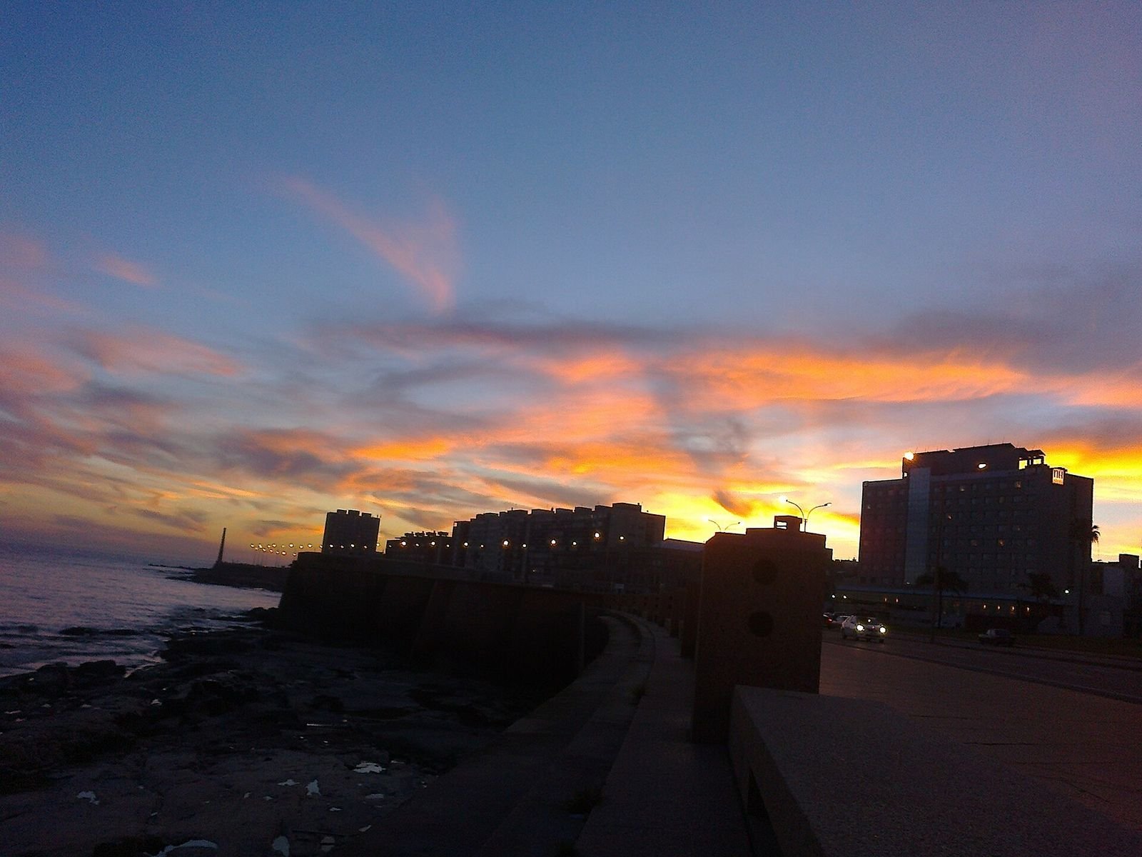 Pôr do sol na rambla de Montevidéu com o farol ao fundo